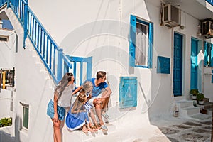 Family vacation in Europe. Parents and kids at street of typical greek traditional village with white walls and colorful