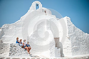 Family vacation in Europe. Parents and kids at street of typical greek traditional village with white walls and colorful