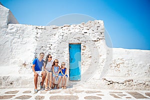 Family vacation in Europe. Parents and kids at street of typical greek traditional village with white walls and colorful