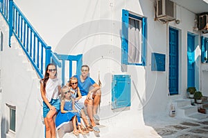Family vacation in Europe. Parents and kids at street of typical greek traditional village with white walls and colorful