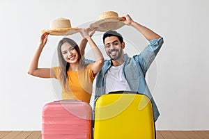 Family vacation. Happy tourist couple taking off hats with greeting gesture standing behind suitcase luggages