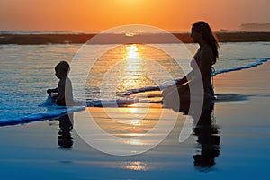 Family vacation. Mother with child on sunset beach
