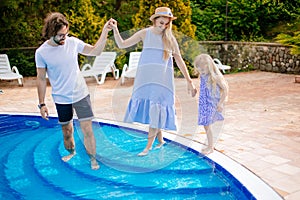 Family vacation in summer. Parents with kid having fun near swimming pool