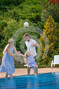 Family vacation in summer. Parents with kid having fun near swimming pool