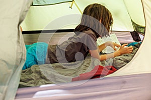 family vacation and travel. joyful boy lies in a tent. travel with children. hiking in the forest and living in a tent