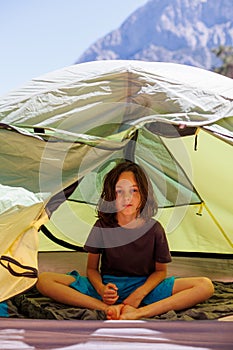 family vacation and travel. joyful boy sits in a tent. travel with children. hiking in the forest and living in a tent