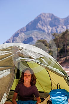 family vacation and travel. joyful boy sits in a tent. travel with children. hiking in the forest and living in a tent