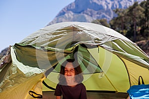 family vacation and travel. joyful boy sits in a tent. travel with children. hiking in the forest and living in a tent