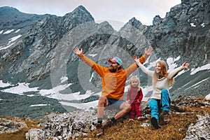 Family vacations father and mother with child hikers happy raised hands enjoying mountain view