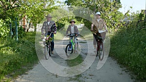 Family vacations, happy male child in sun hat with their cheerful grandparents ride bicycles during outdoor activities