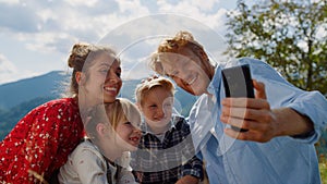 Family video call nature at sunny day. Parents with children using cellphone.