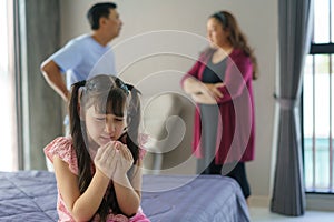 Family violence and family conflict concept, sad little girl with blur of mother fighting father with quarrel at home