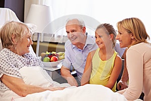 Family Visit To Grandmother In Hospital Bed