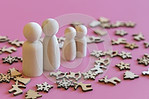 Family is waiting for the new year. wooden figurines of papa`s mom and two children on a pink background with Christmas