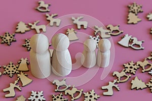 Family is waiting for the new year. wooden figurines of papa`s mom and two children on a pink background with Christmas