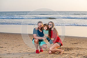 Family walk along sea beach. Happy parents with child playing on beach. Spending summer time in nature.