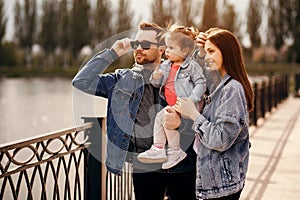 Family walk, father and mother hold their daughter in their arms, the family walks near the river, sunset