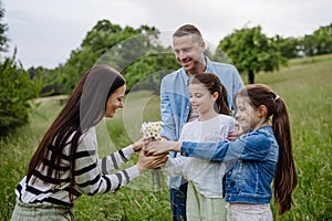 Family on walk in forest, going through meadow. Daughters picking flowers, giving them to mother. Concept of family