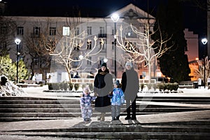 Family walk through the night city in the winter. A woman and three children in evening