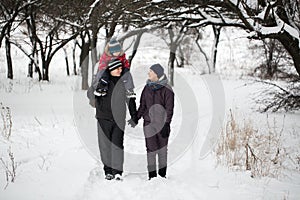 Family walk through the snow-covered forest in winter.