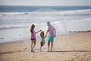 Family walking on beach. Happy father, mother and son child walking on sand beach. Summer vacations with children.