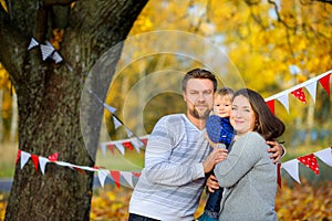 Family walking in beautiful autumn park, hugging and smiling