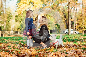 Family walking with dog in autumn park. Fashionable mother and daughter on a walk