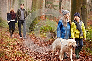 Family Walking Dog Through Winter Woodland