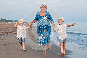 Family walking on the evening beach during sunset.Grandmother and two grandsons.