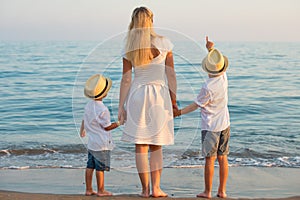 Family walking on the evening beach during sunset.Mother and two sons.