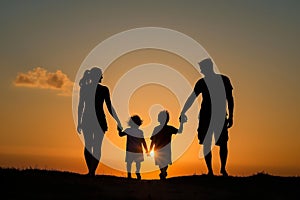 Family walking hand in hand into sunset