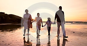 Family, walking and holding hands on beach at sunset in summer, holiday or vacation with love. Parents, children or