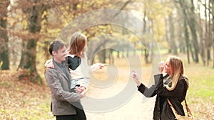 Family walking in park, father carries daughter in his arms and mom tickles her