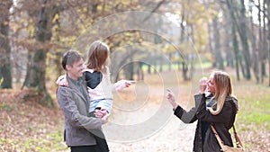 Family walking in park, father carries daughter in his arms and mom tickles her