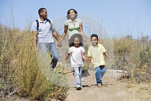 Family walking on path holding hands and smiling