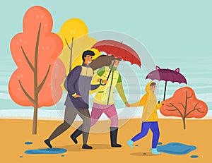 Family walking in the rain with umbrella and wearing raincoats in the city park in autumn season