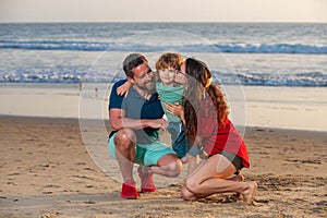 Family walking to the beach on a sunny day. Sea vacation. Parents and children hugging at ocean shore at sunset. Summer