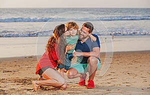 Family walking to the beach on a sunny day. Sea vacation. Parents and children hugging at ocean shore at sunset. Summer