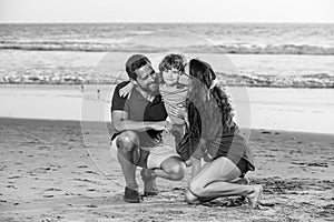 Family walking to the beach on a sunny day. Sea vacation. Parents and children hugging at ocean shore at sunset. Summer