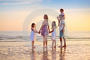 Family walking on tropical beach at sunset