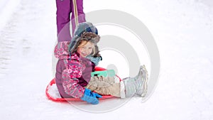 Family walking in a winter park. Parents with child on sled