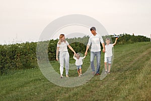 Family walks in a field and playing with toy plane