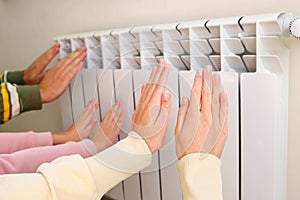 The family warms their hands near the radiator