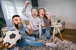 Family watching football match at home