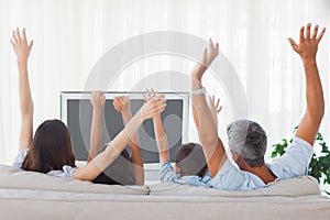 Family watching televison and rising theirs arms photo