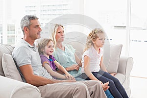 Family watching TV while sitting on sofa