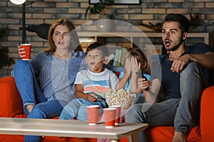 Family watching TV on sofa in evening