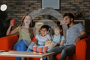 Family watching TV on sofa in evening