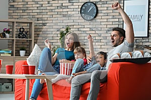 Family watching TV on sofa at home