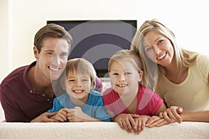 Family Watching Widescreen TV At Home